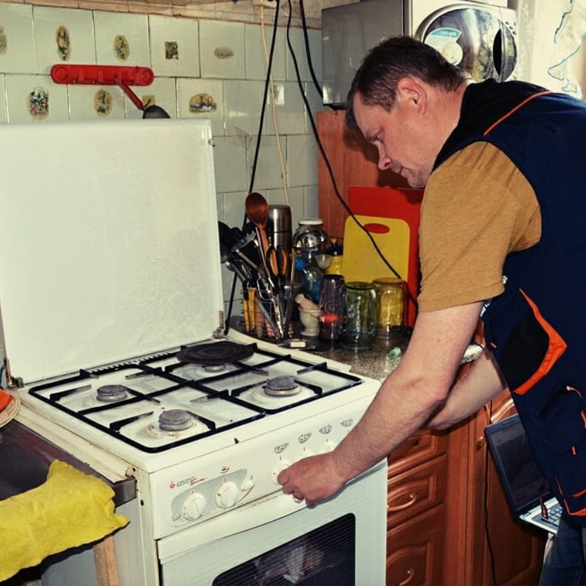 мастер выполняет ремонт газовой плиты